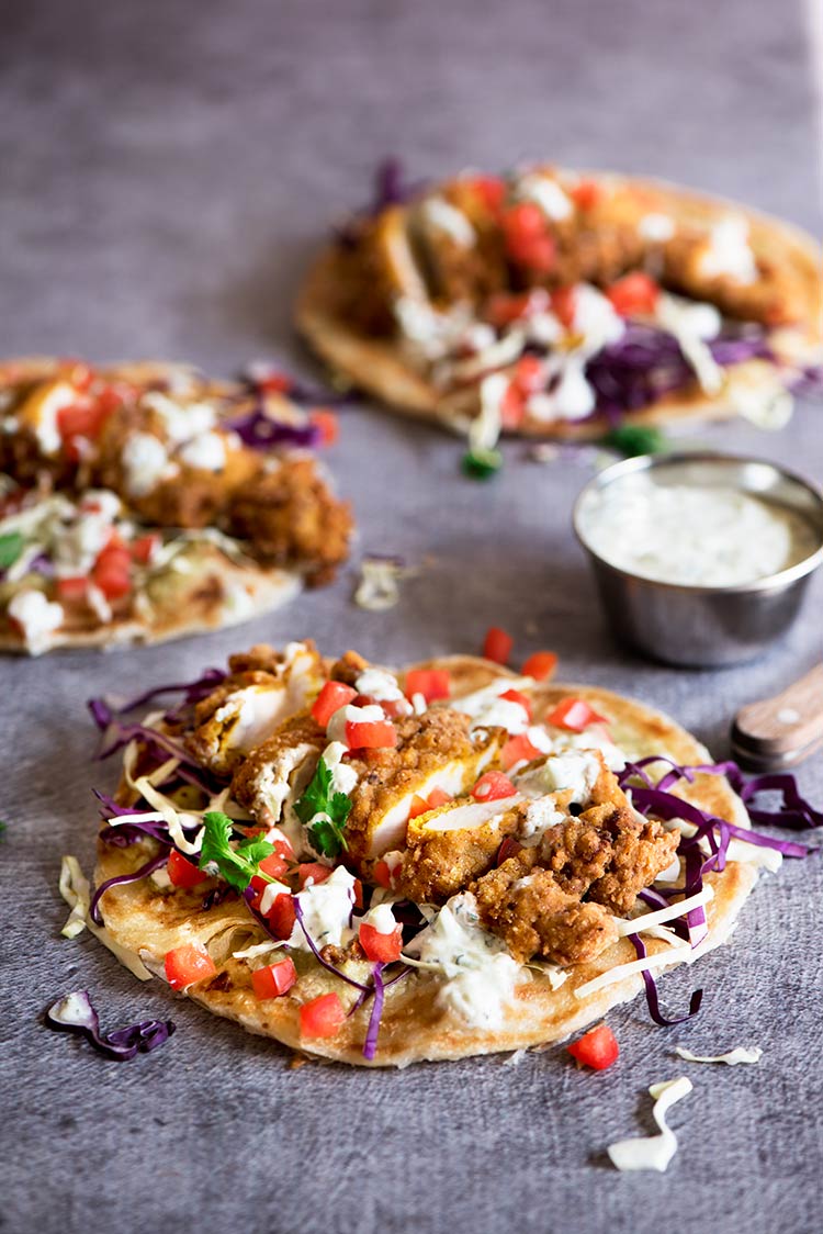 Uber crispy outside, moist and tender inside spiced fried chicken tenders with tomatillo chutney, cucumber mint raita all wrapped in flaky, crispy roti paratha.