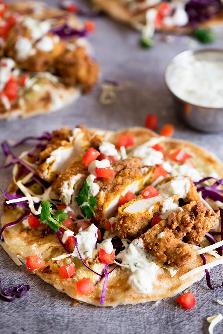 Uber crispy outside, moist and tender inside spiced fried chicken tenders with tomatillo chutney, cucumber mint raita all wrapped in flaky, crispy roti paratha.